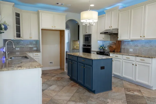 a kitchen with granite countertop a sink a counter top space and cabinets