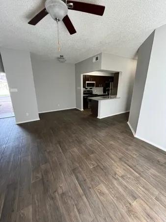 a view of an empty room with wooden floor ceiling fan