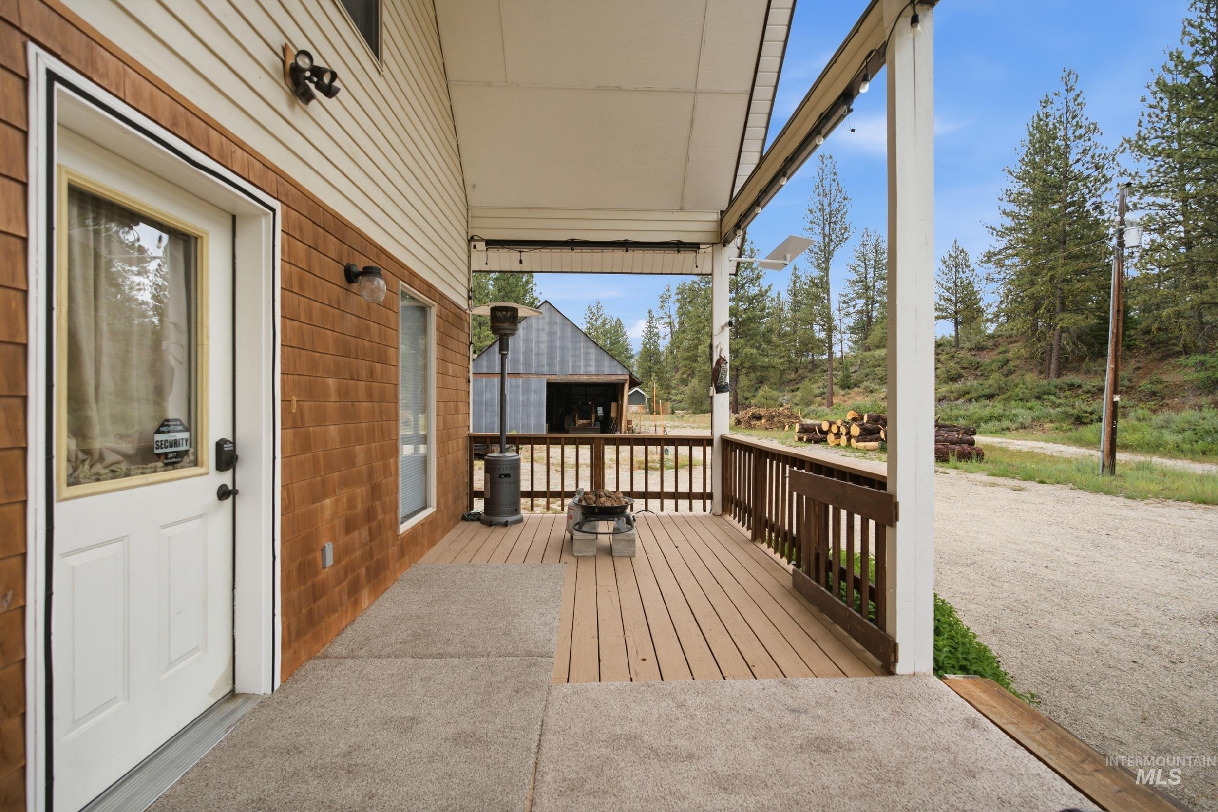 3980 North Pine-Featherville Road Mountain Home, ID 83647 - Photo 33 of 35 Covered porch with composite decking, white entry door with glass pane, horizontal siding, and natural wood shake siding accents