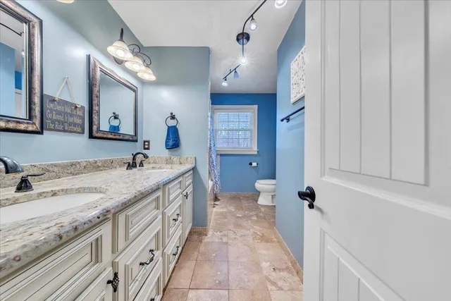 a spacious bathroom with a granite countertop sink a mirror and a bathtub