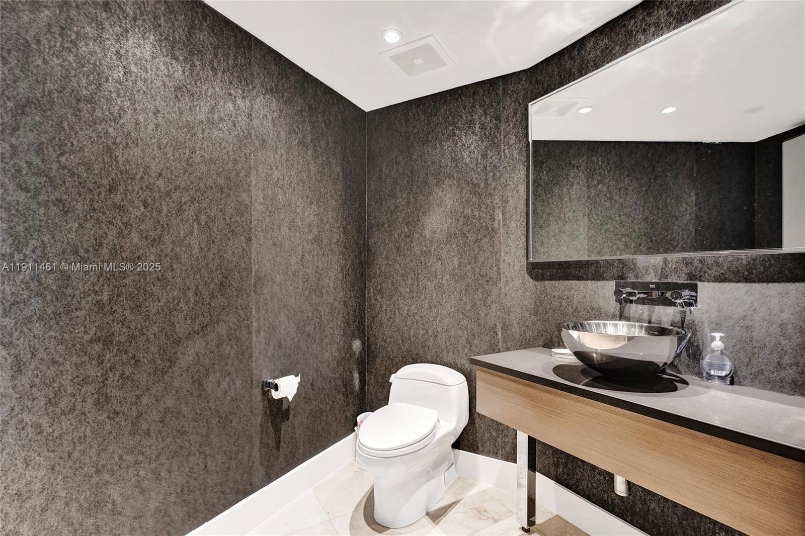 19111 Collins Avenue, Unit 1602 Sunny Isles Beach, FL 33160 - Photo 44 of 93 a bathroom with a toilet a sink and mirror