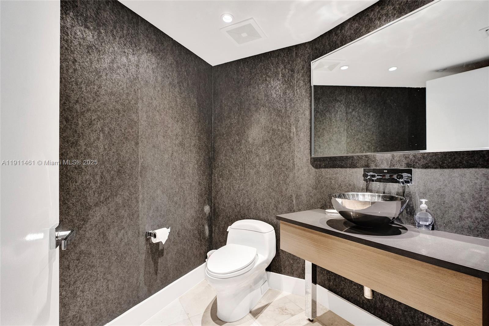 19111 Collins Avenue, Unit 1602 Sunny Isles Beach, FL 33160 - Photo 53 of 93 a bathroom with a sink mirror and toilet