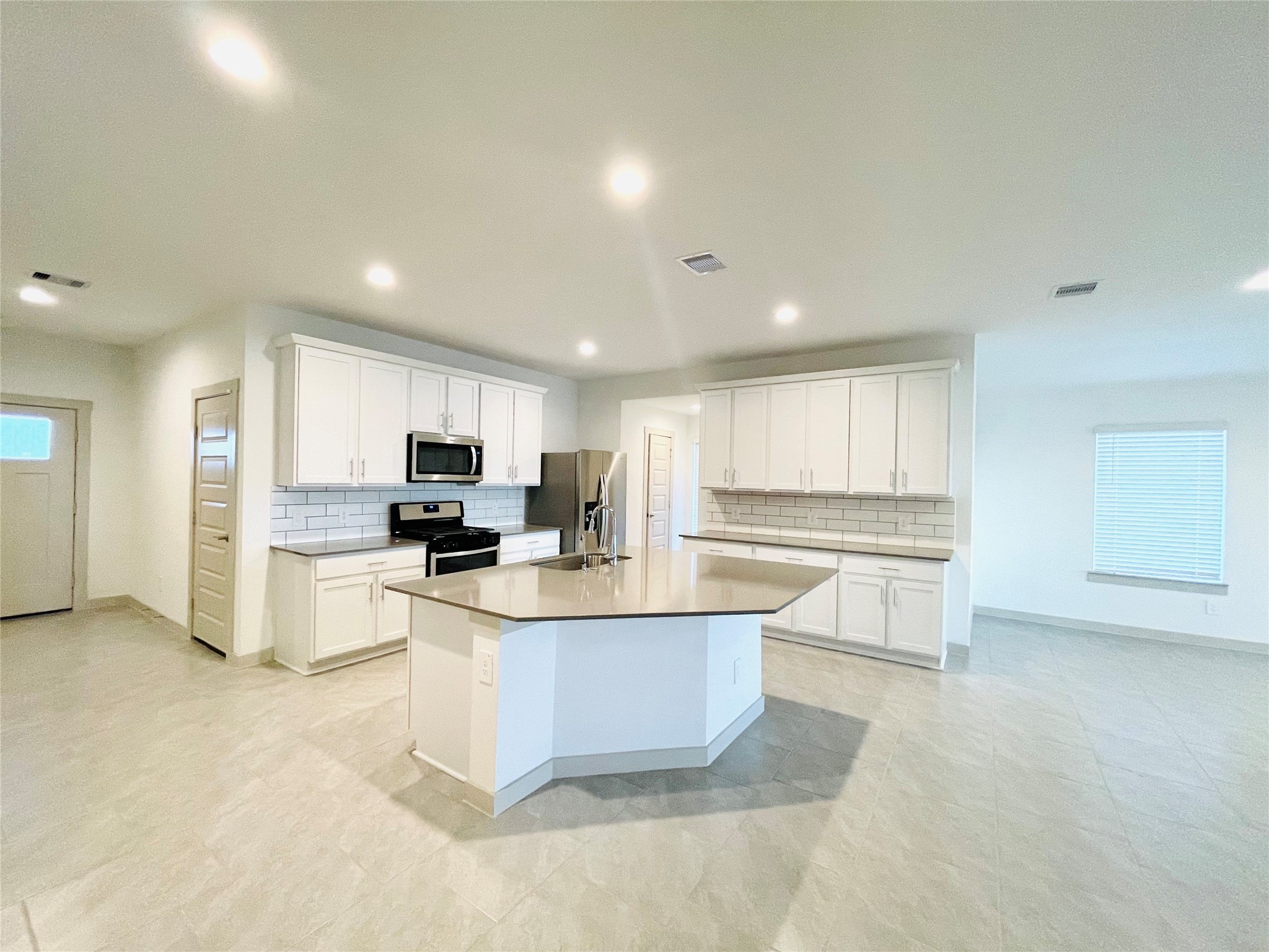 28935 Yachting Point Lane Katy, TX 77494 - Photo 9 of 38 a large white kitchen with kitchen island a sink a stove a refrigerator and white cabinets