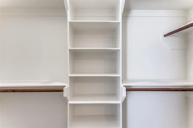 an empty room with closet and a chandelier fan