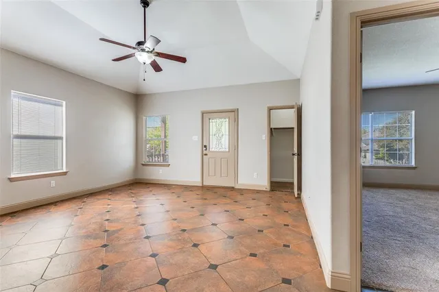 a view of an empty room with window and chandelier fan