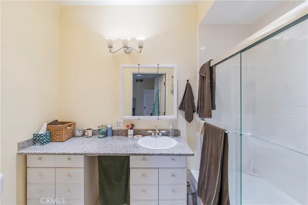 a bathroom with a granite countertop sink a mirror and shower