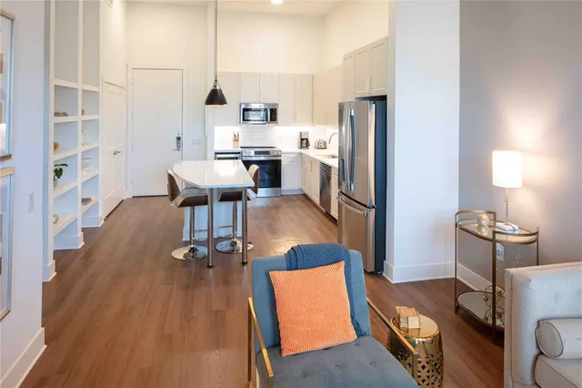 a kitchen with stainless steel appliances a refrigerator a stove a sink dishwasher and a dining table with wooden floor