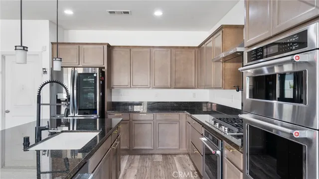 a kitchen with stainless steel appliances granite countertop a stove white cabinets a sink and dishwasher