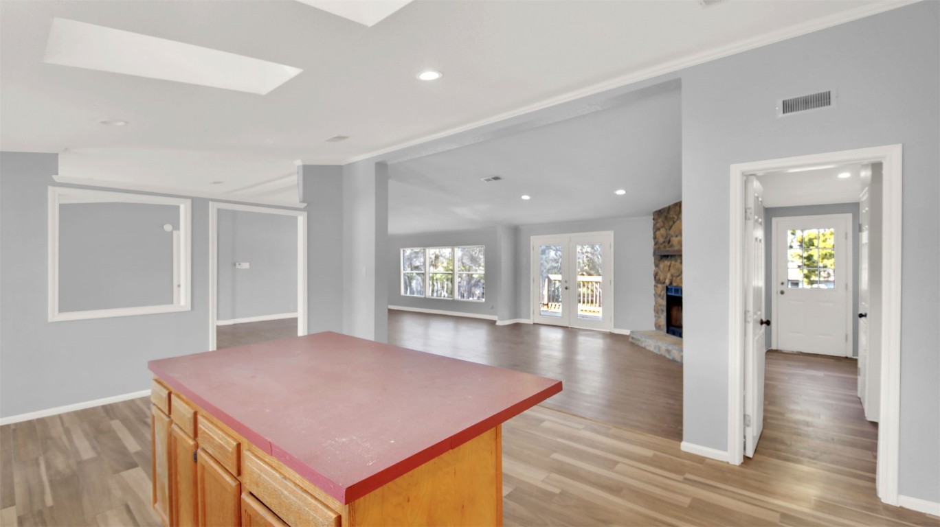 120 Webberwood Way Elgin, TX 78621 - Photo 17 of 36 Kitchen with a skylight, light wood-style floors, french doors, a center island, and lofted ceiling