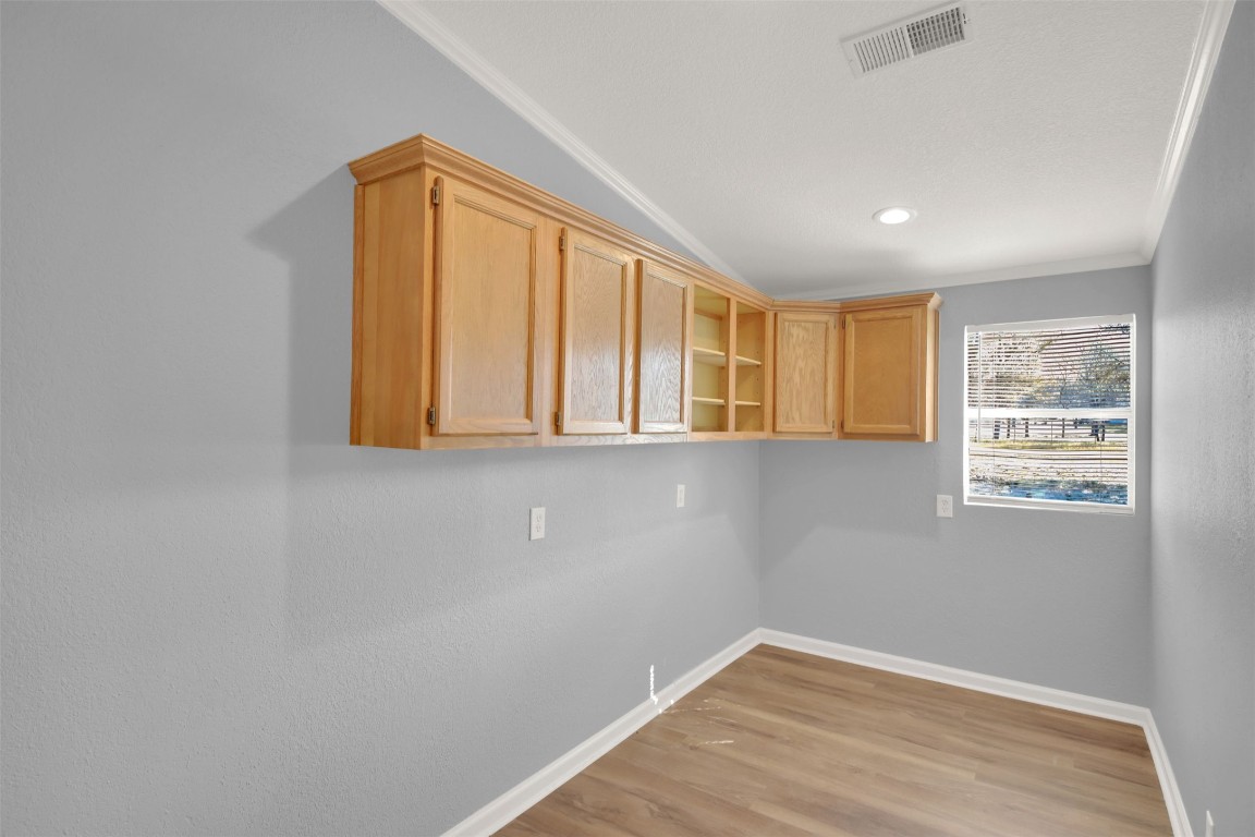 120 Webberwood Way Elgin, TX 78621 - Photo 20 of 36 Empty room with crown molding, light wood-type flooring, and lofted ceiling