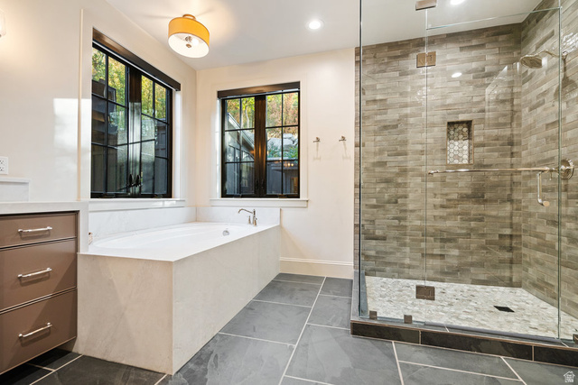 1141 South Oak Leaf Lane Springville, UT 84663 - Photo 60 of 147 Spacious bathroom featuring a frameless glass shower enclosure, a built-in soaking tub, dark slate tile flooring, a built-in vanity with drawer storage, and two large windows with dark trim