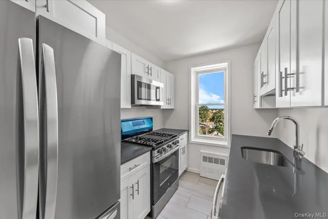 a kitchen with stainless steel appliances granite countertop a refrigerator a stove a sink and a microwave with wooden floor