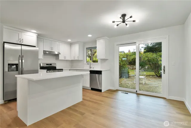 a kitchen with stainless steel appliances granite countertop a stove a refrigerator a sink and a oven with wooden floor