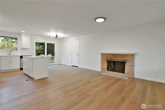 an empty room with kitchen and fireplace