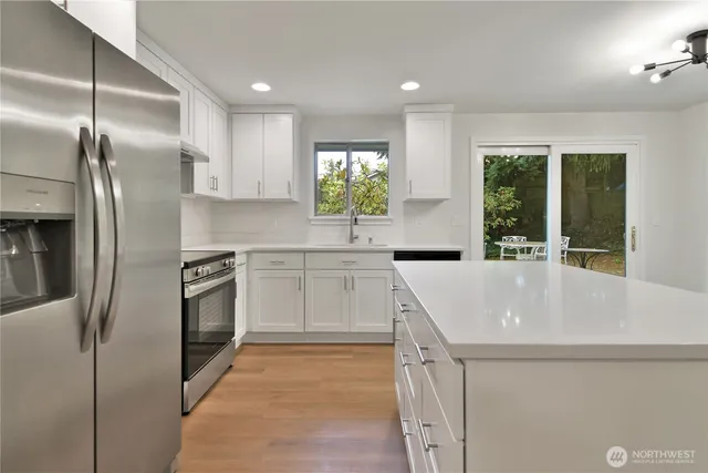 a kitchen with stainless steel appliances granite countertop a sink a stove and a refrigerator