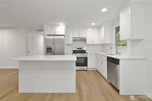 a kitchen with kitchen island sink stove and white cabinets