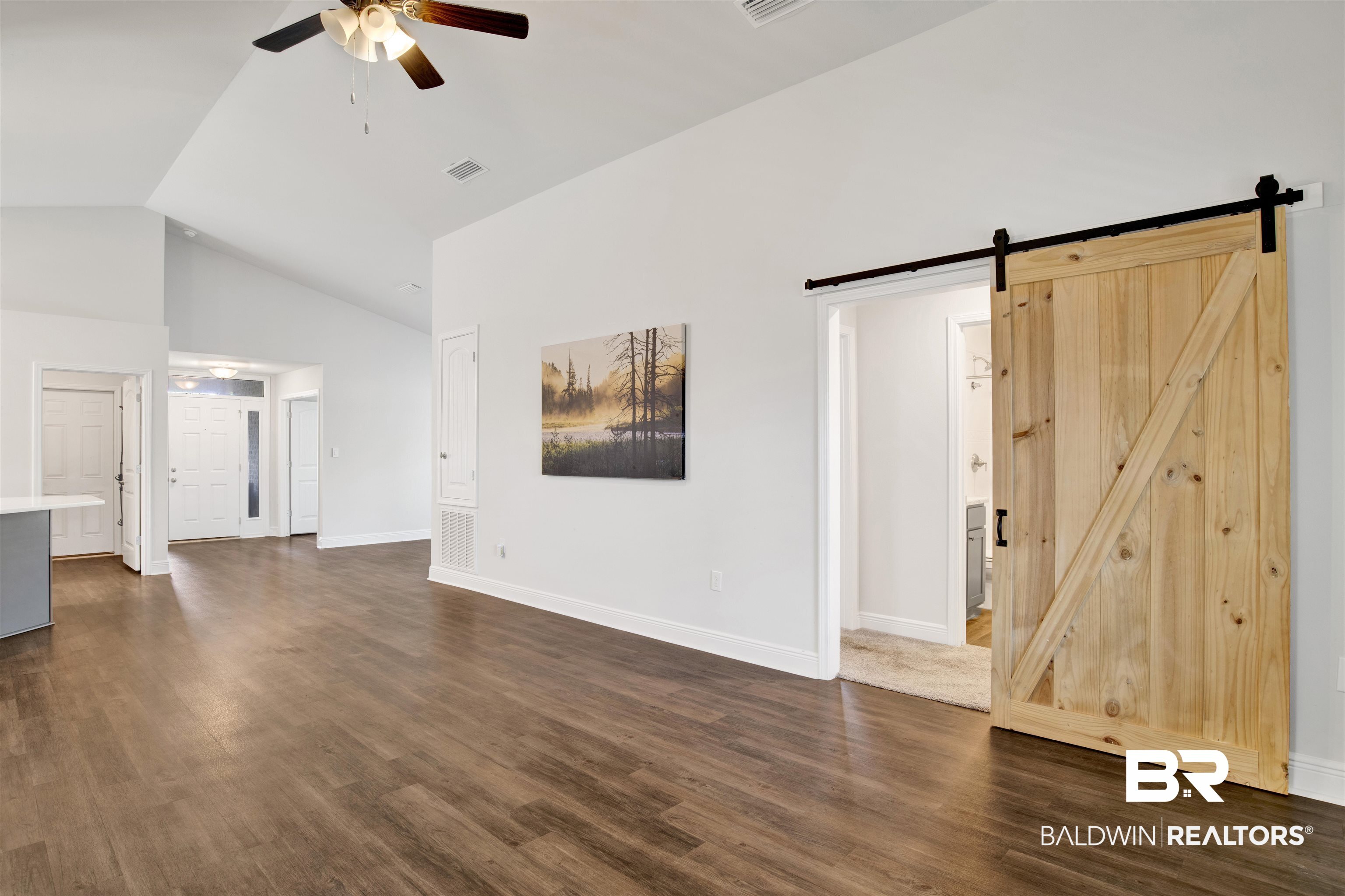 22462 Respite Lane Foley, AL 36535 - Photo 14 of 22 Unfurnished living room featuring dark wood-type flooring, a barn door, high vaulted ceiling, and ceiling fan