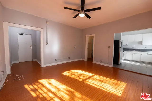 a view of empty room with wooden floor and fan