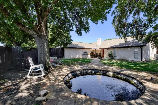 a view of a patio with table and chairs under an umbrella with large tree