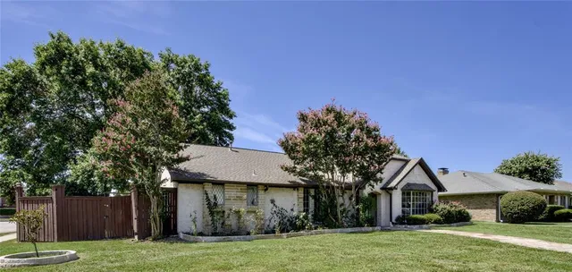 a front view of a house with a garden and trees