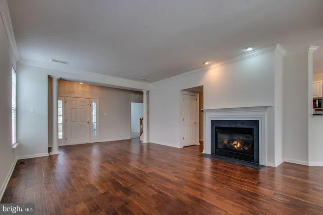 a view of an empty room with wooden floor fireplace and a window