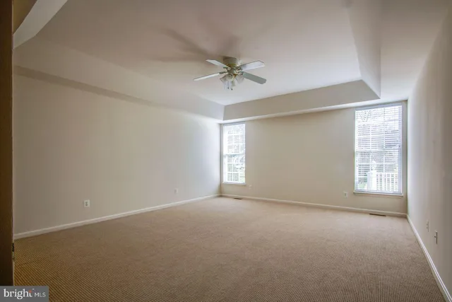 an empty room with windows and ceiling fan