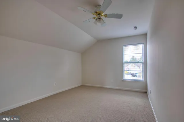 an empty room with windows and ceiling fan
