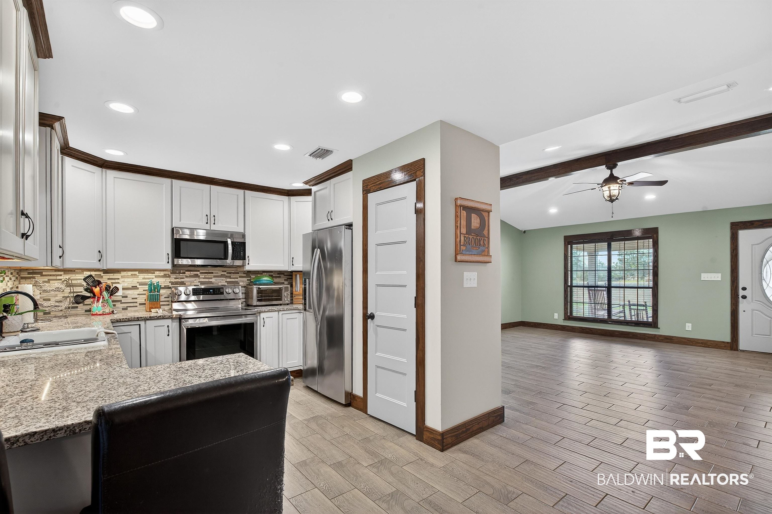 29635 Gardner Road Elberta, AL 36530 - Photo 66 of 66 Kitchen with appliances with stainless steel finishes, beam ceiling, light stone countertops, backsplash, and open floor plan
