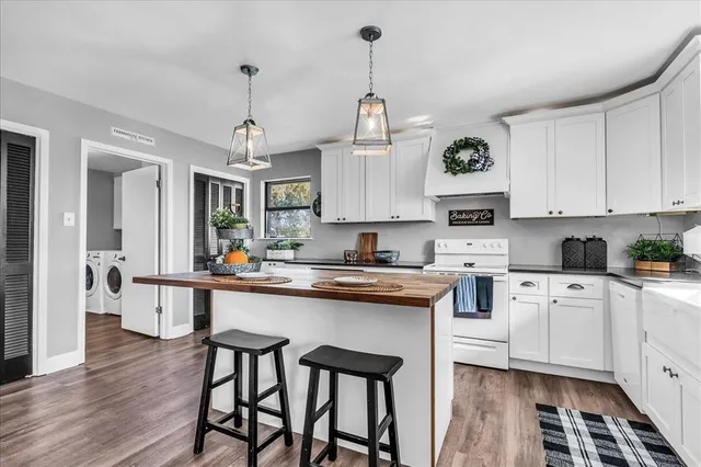 a kitchen with stainless steel appliances granite countertop a stove a sink dishwasher a refrigerator and white cabinets with wooden floor