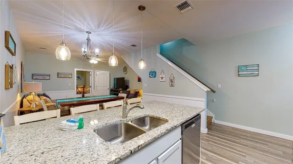 a kitchen with a sink a counter top space and living room view