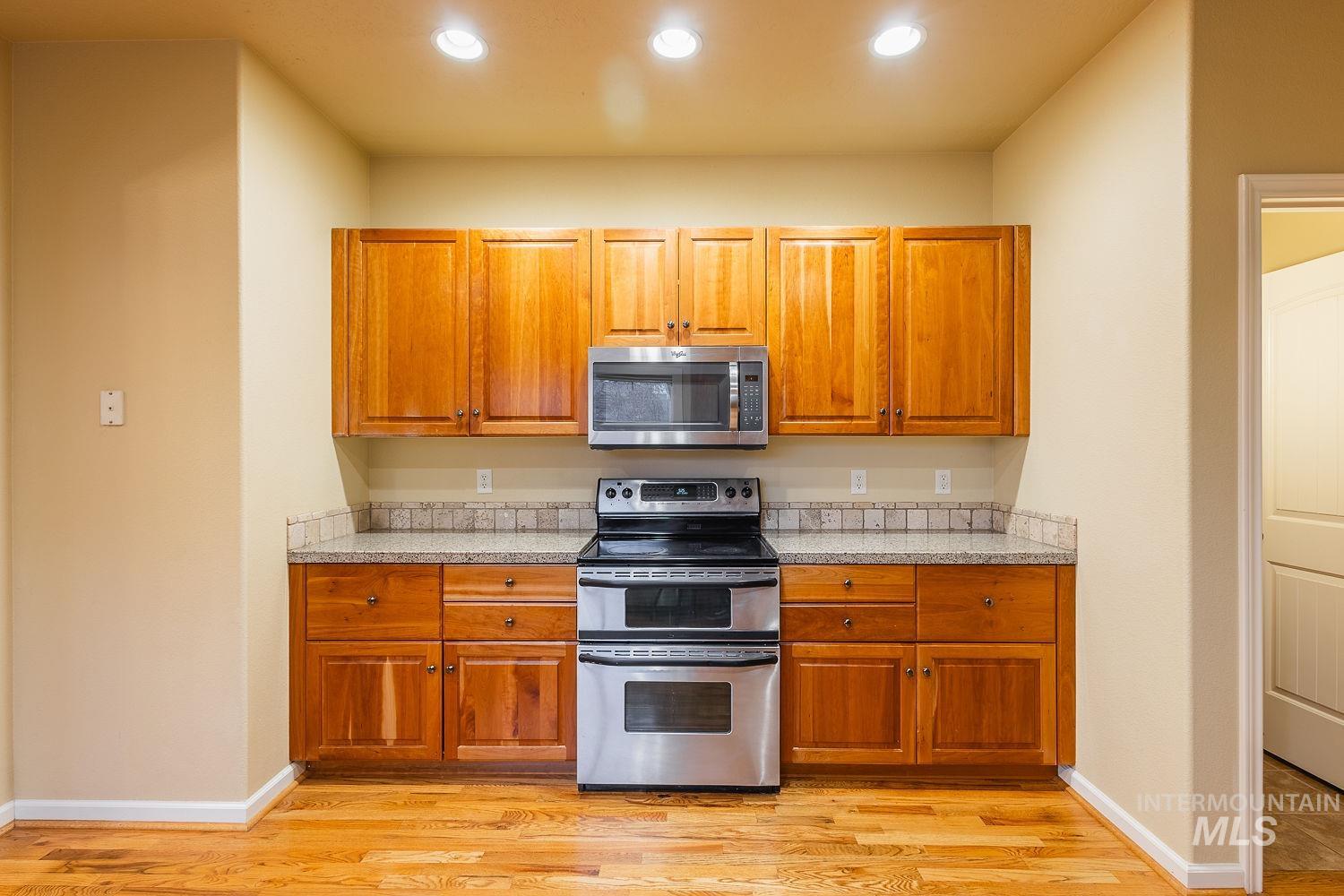 215 South Spring Lake Way Star, ID 83669 - Photo 16 of 50 Kitchen with stainless steel appliances, brown cabinets, light wood-style flooring, light stone countertops, and recessed lighting