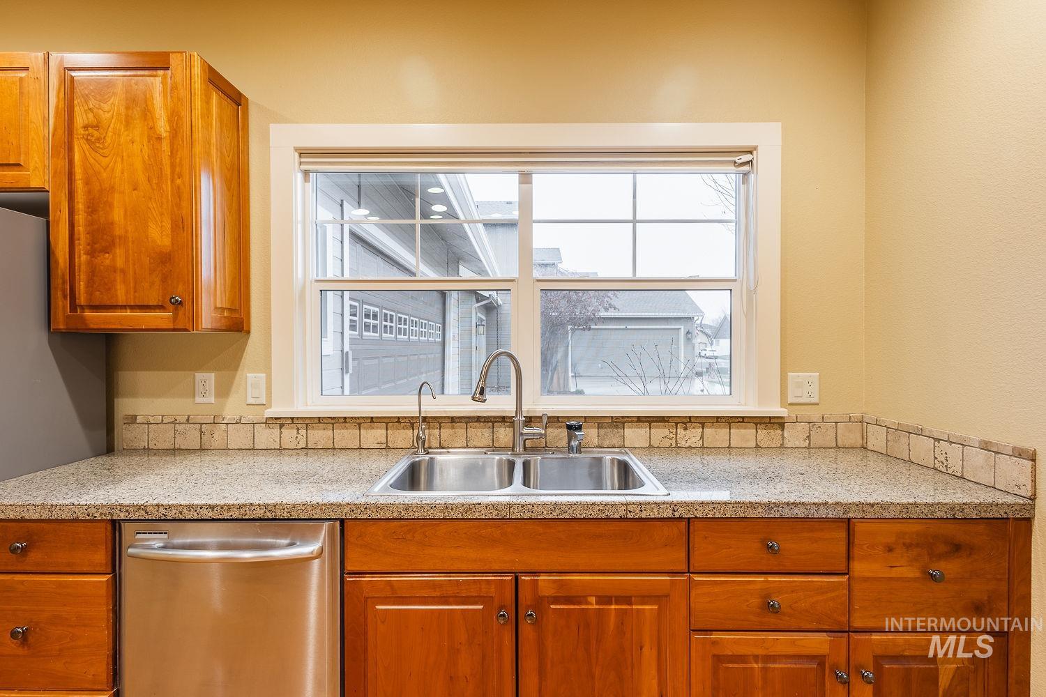 215 South Spring Lake Way Star, ID 83669 - Photo 17 of 50 Kitchen with brown cabinets, stainless steel dishwasher, healthy amount of natural light, and light stone counters