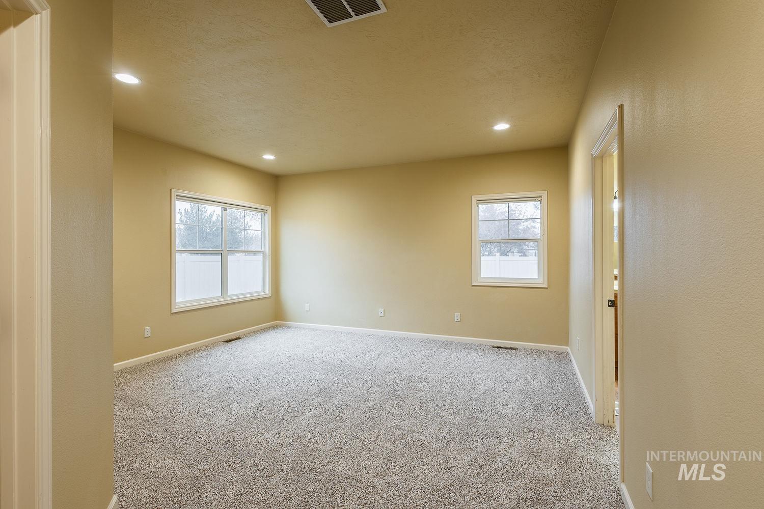 215 South Spring Lake Way Star, ID 83669 - Photo 18 of 50 Empty room featuring light colored carpet, recessed lighting, and a textured ceiling