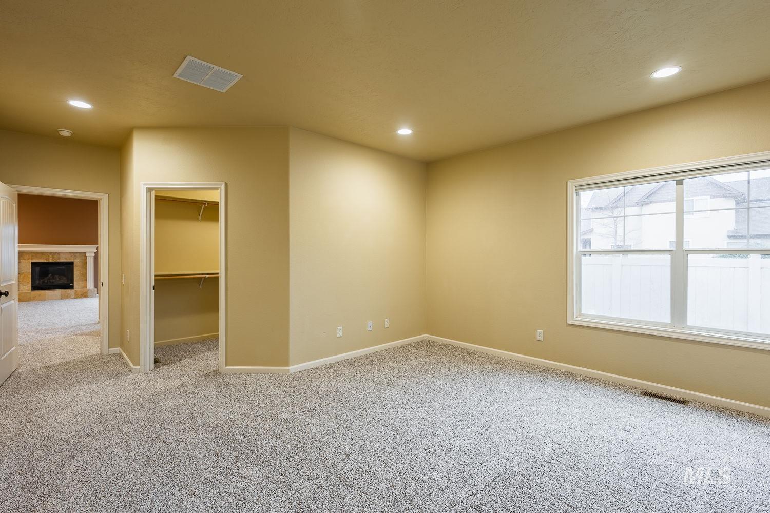 215 South Spring Lake Way Star, ID 83669 - Photo 19 of 50 Unfurnished bedroom with a walk in closet, a fireplace, light carpet, and recessed lighting