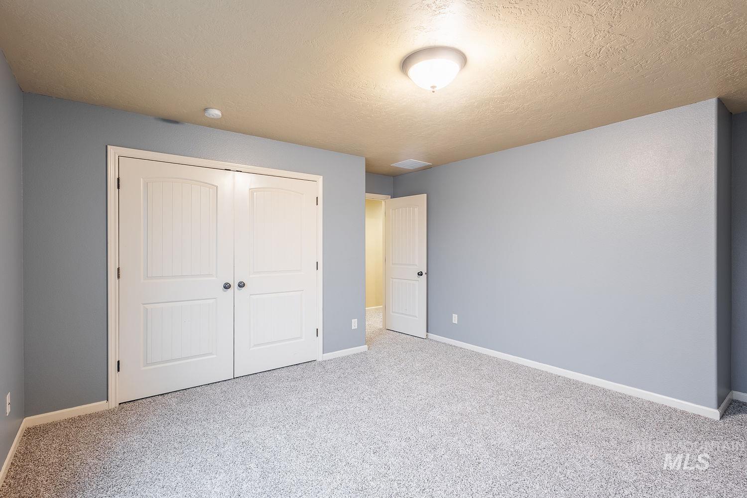 215 South Spring Lake Way Star, ID 83669 - Photo 28 of 50 Unfurnished bedroom featuring carpet floors, a textured ceiling, and a closet