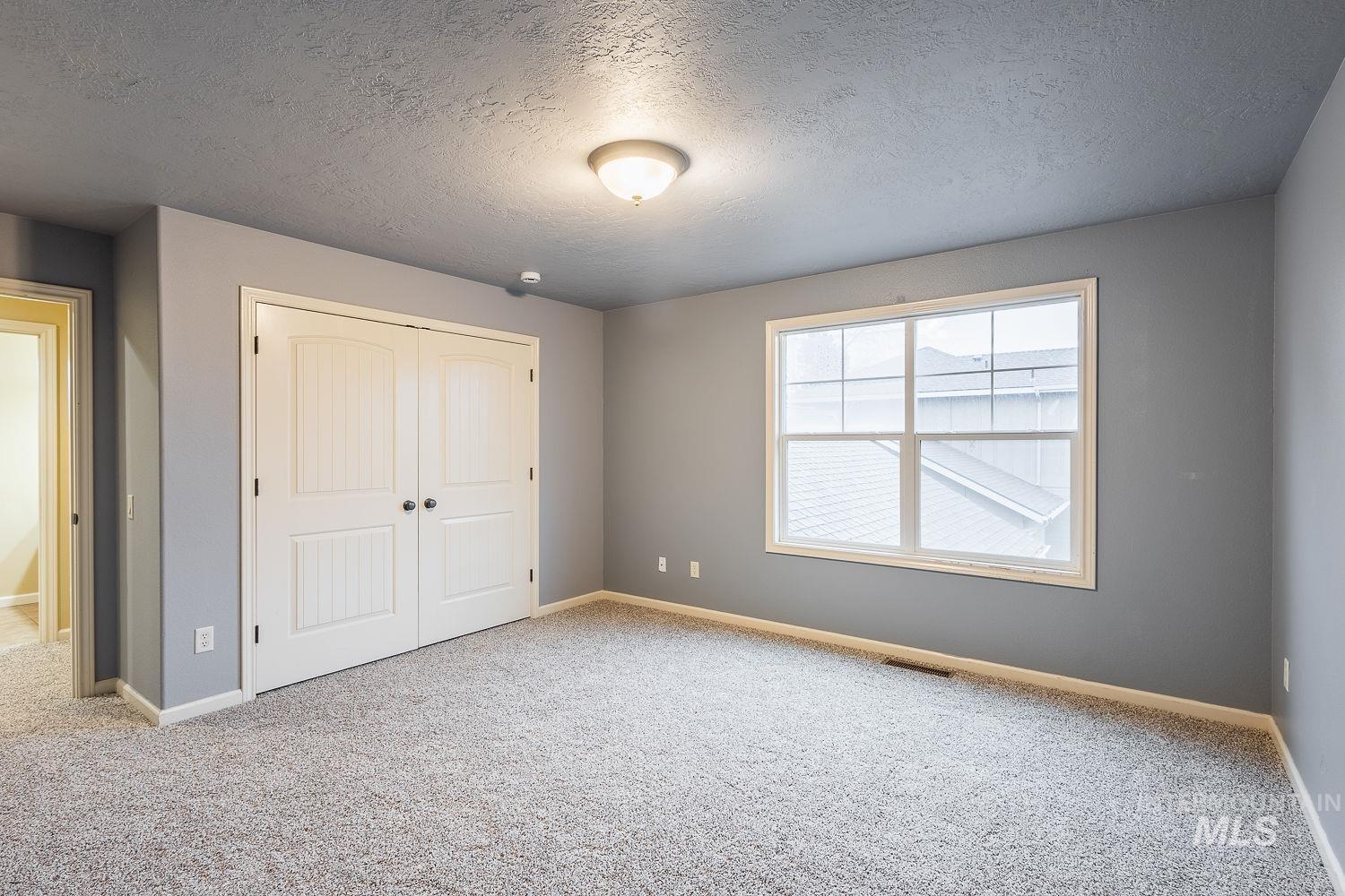 215 South Spring Lake Way Star, ID 83669 - Photo 32 of 50 Unfurnished bedroom featuring a textured ceiling, a closet, and carpet floors