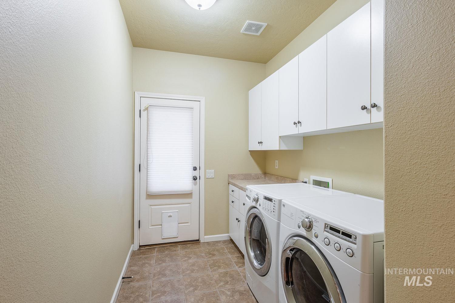 215 South Spring Lake Way Star, ID 83669 - Photo 35 of 50 Washroom featuring cabinet space, separate washer and dryer, light tile patterned flooring, and a textured ceiling