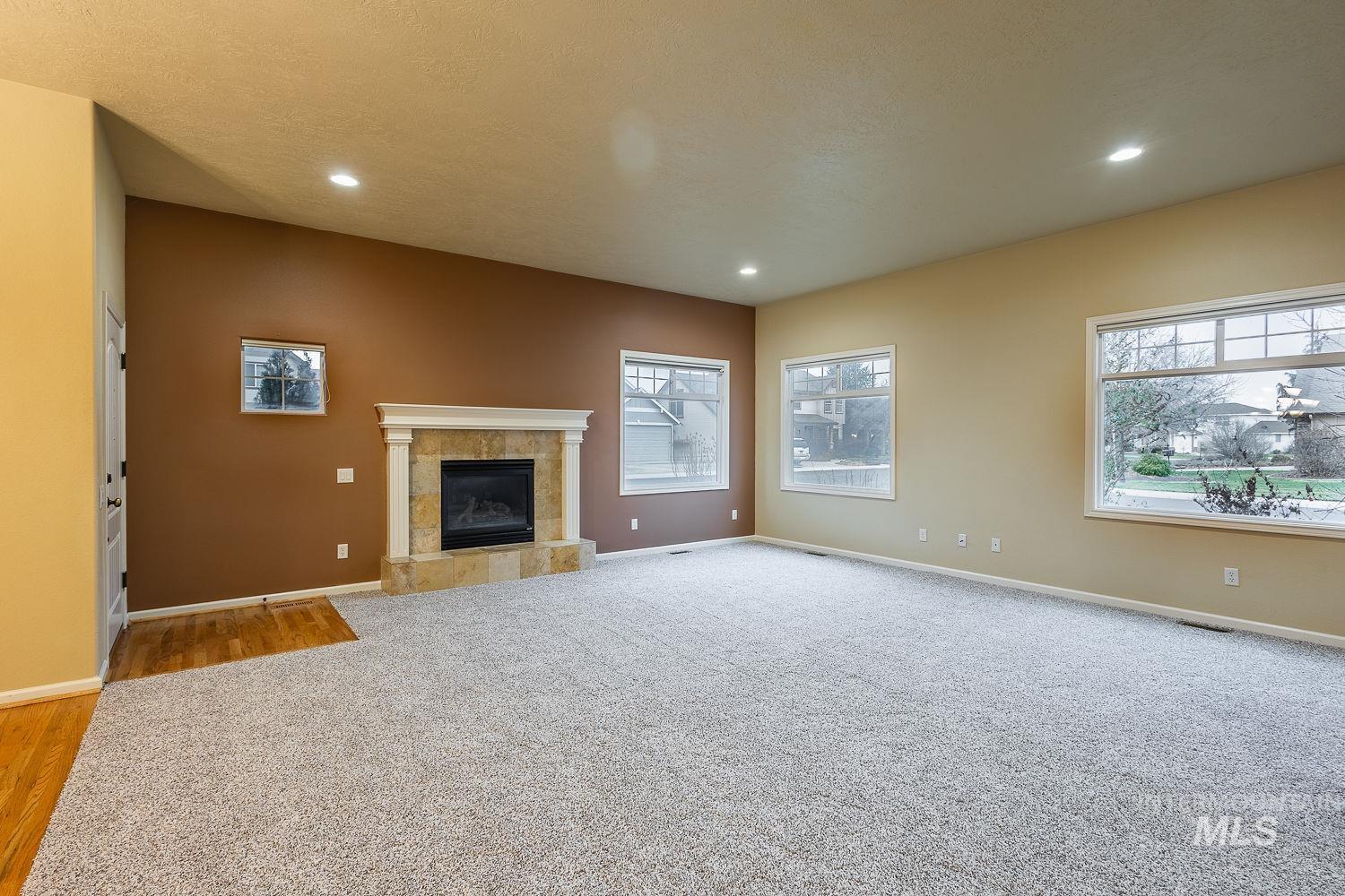 215 South Spring Lake Way Star, ID 83669 - Photo 10 of 50 Unfurnished living room featuring a tile fireplace, light carpet, and recessed lighting
