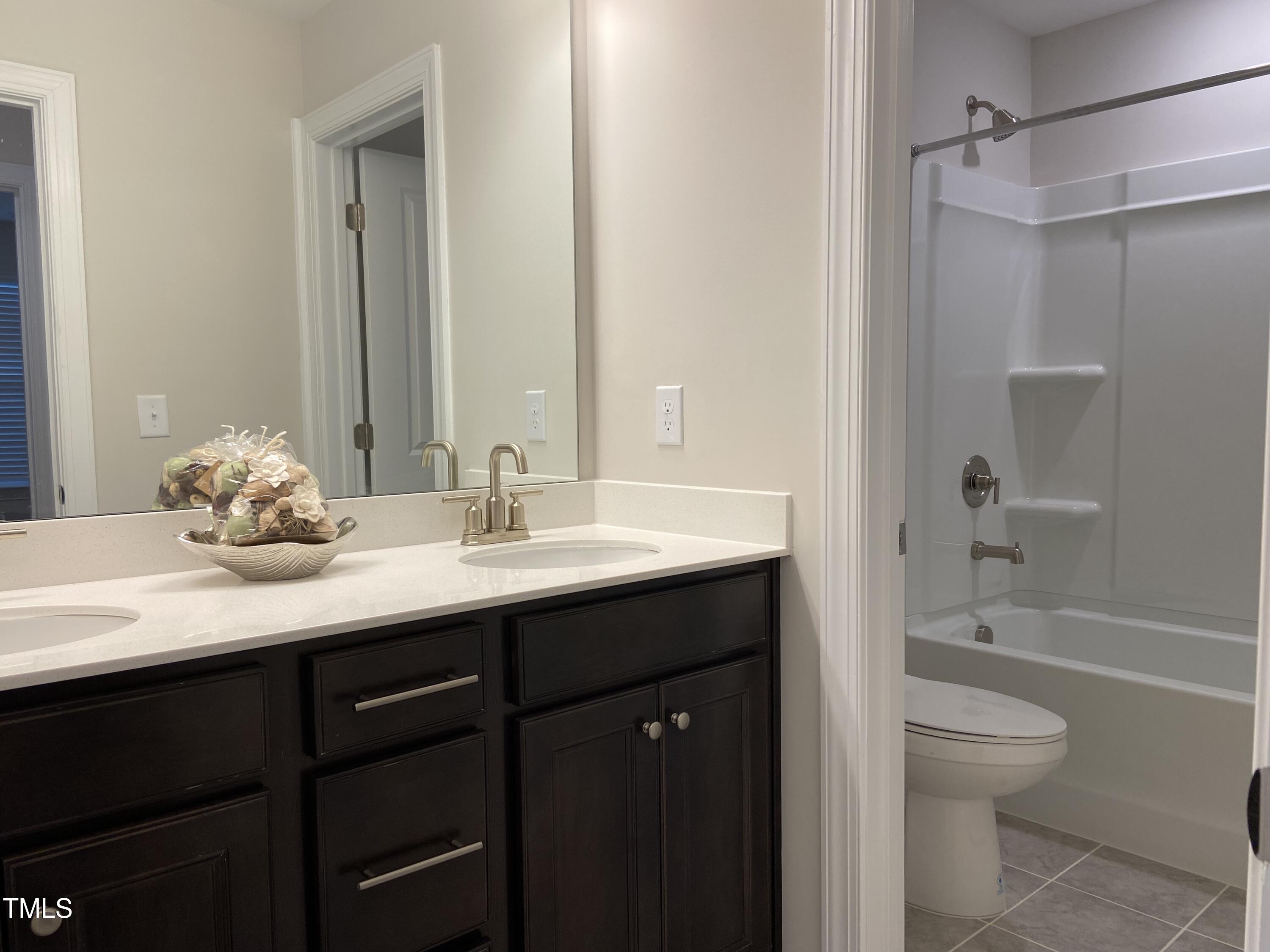 856 Patriot Summit Lane Apex, NC 27523 - Photo 24 of 25 a bathroom with a granite countertop sink toilet a shower and a bathtub