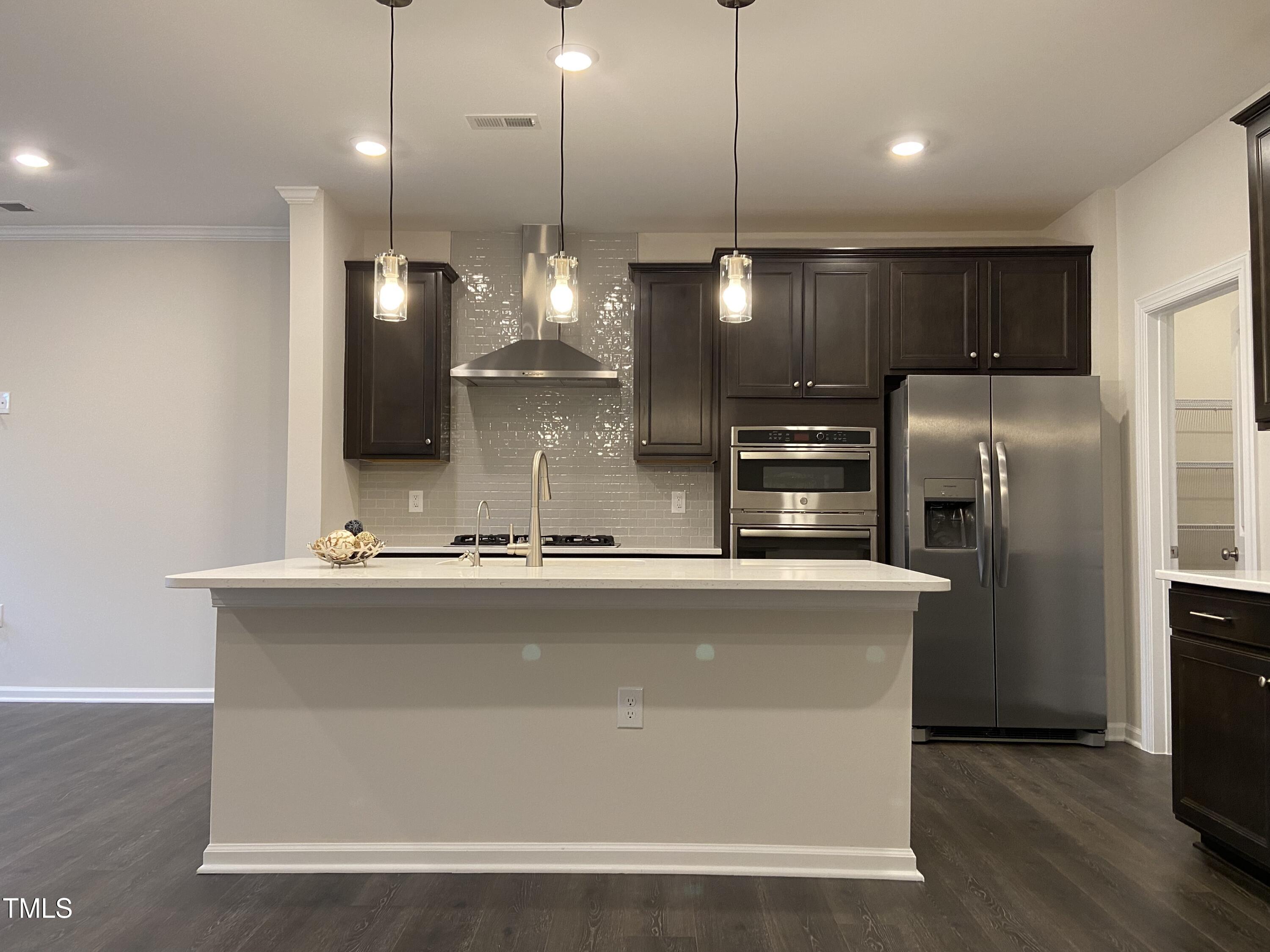 856 Patriot Summit Lane Apex, NC 27523 - Photo 4 of 25 a view of a kitchen with a stove a refrigerator a sink and a wooden floor
