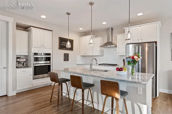 a kitchen with kitchen island granite countertop a table chairs refrigerator and microwave