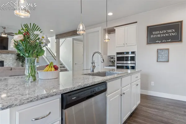 a kitchen with stainless steel appliances granite countertop a sink a counter space cabinets and a potted plant