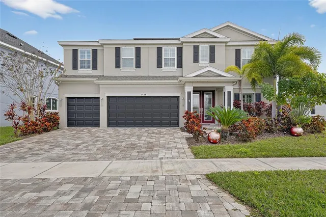 a view of a white house next to a yard with big trees
