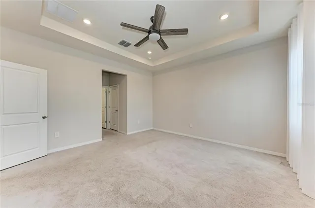 an empty room with a chandelier fan and closet area
