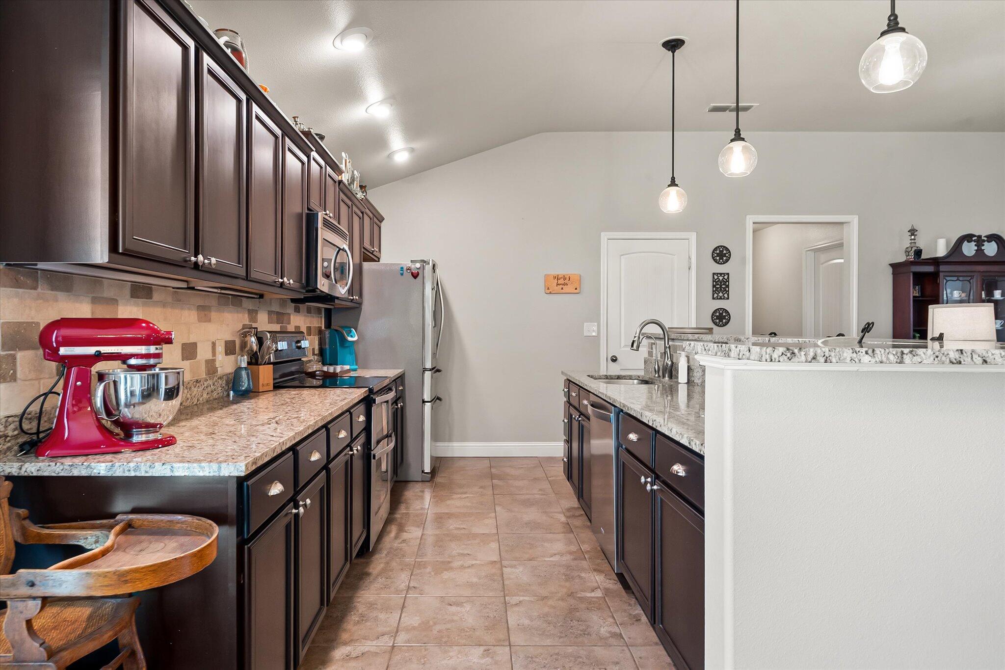 3106 128th Street Lubbock, TX 79423 - Photo 15 of 44 a kitchen with stainless steel appliances granite countertop a sink a stove top oven a counter space and cabinets