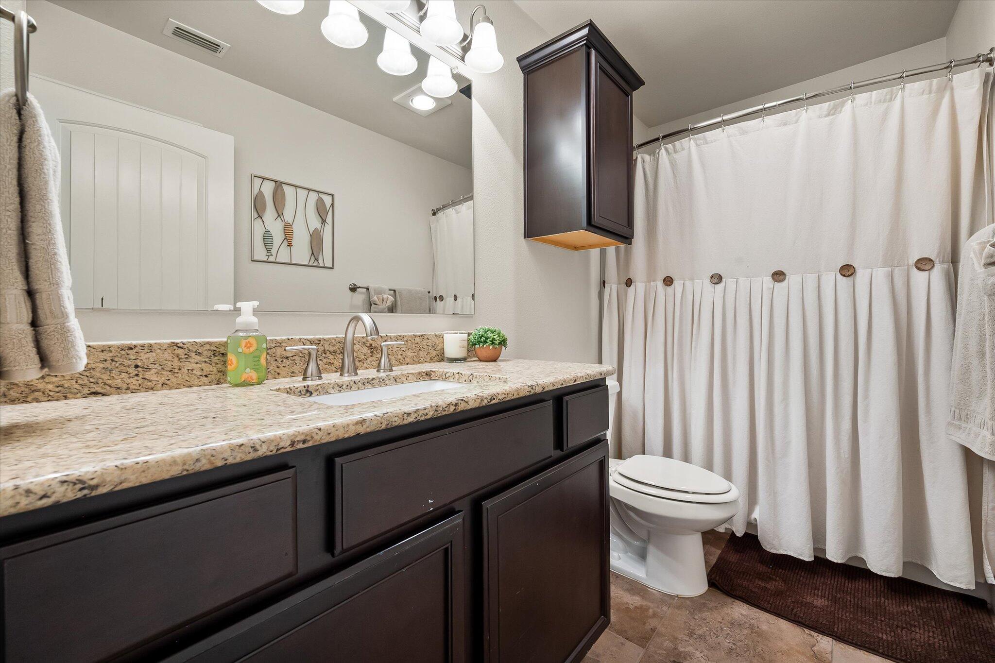 3106 128th Street Lubbock, TX 79423 - Photo 30 of 44 a bathroom with a granite countertop sink a toilet and a mirror