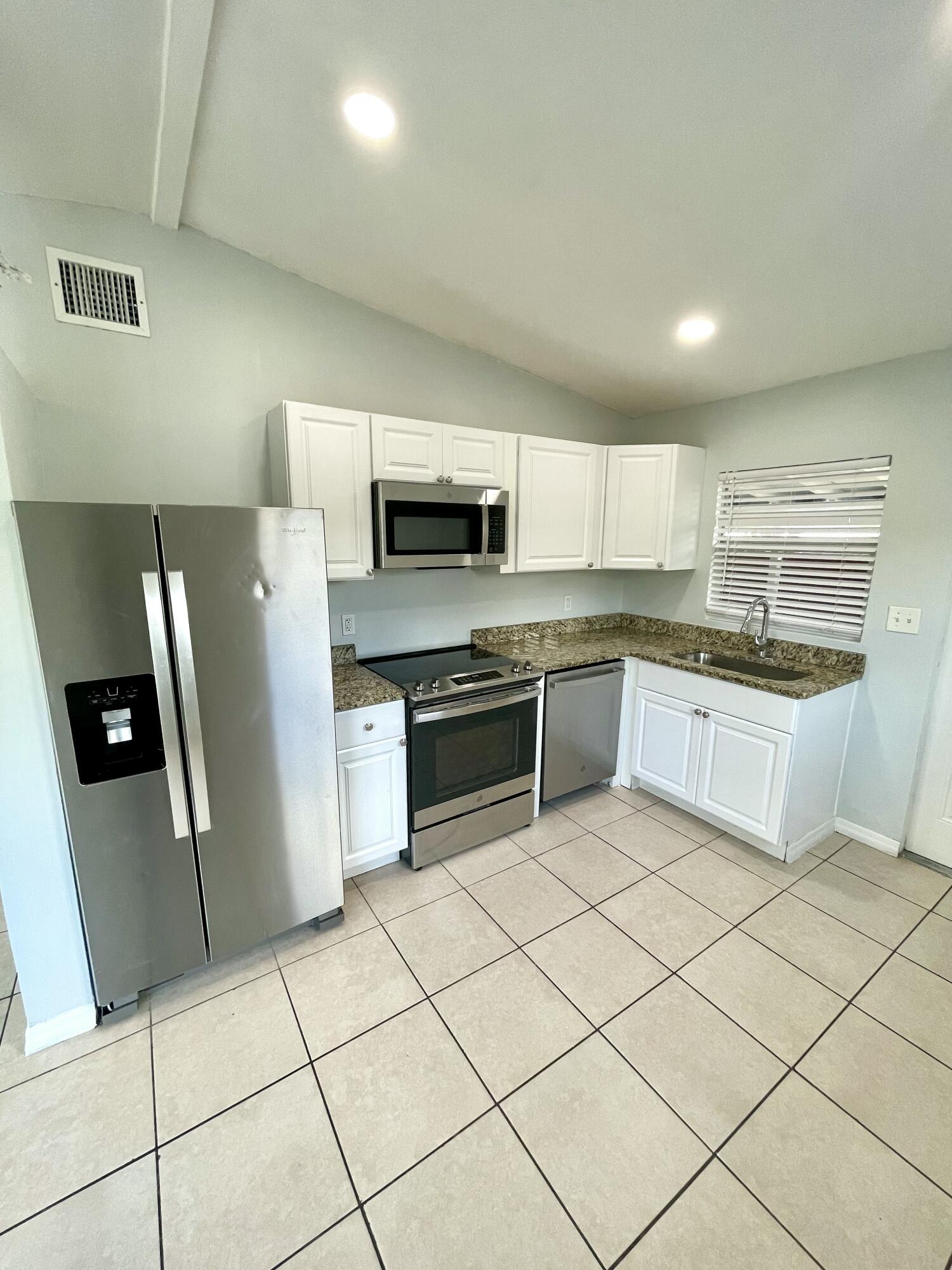 640 54th Street, Unit A West Palm Beach, FL 33407 - Photo 6 of 13 a kitchen with stainless steel appliances a refrigerator sink and microwave