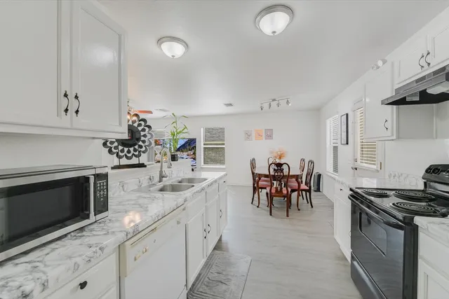 a kitchen with granite countertop sink stove and white cabinets