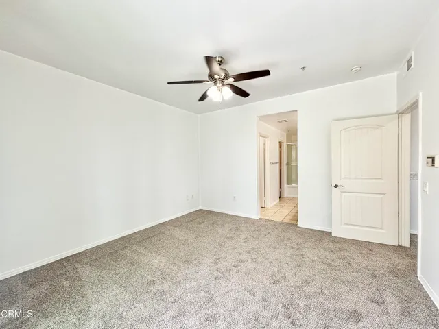 an empty room with closet and a ceiling fan