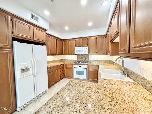 a kitchen with granite countertop wooden cabinets and stainless steel appliances